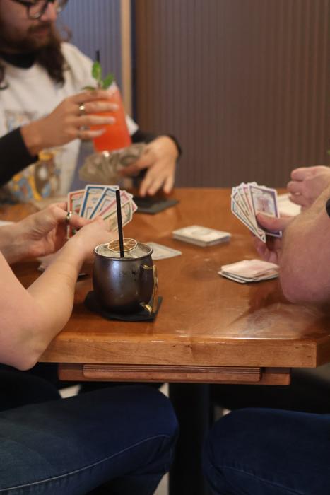 Guests playing cards with drinks in hand